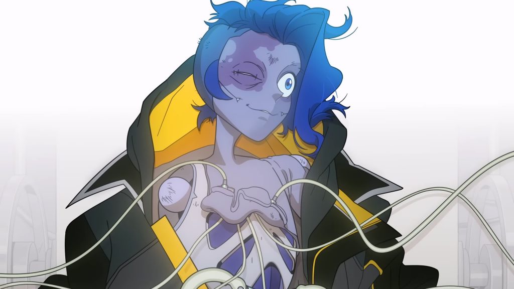 An android sits connected to cables, wearing a borrowed coat.